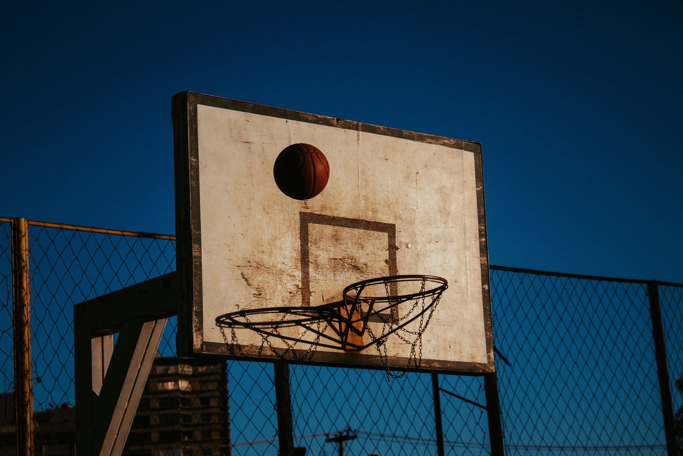 A worn basketball hoop against a deep blue sky.